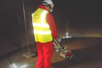 Technician scanning a storage tank floor with MFL equipment during an out-of-service inspection